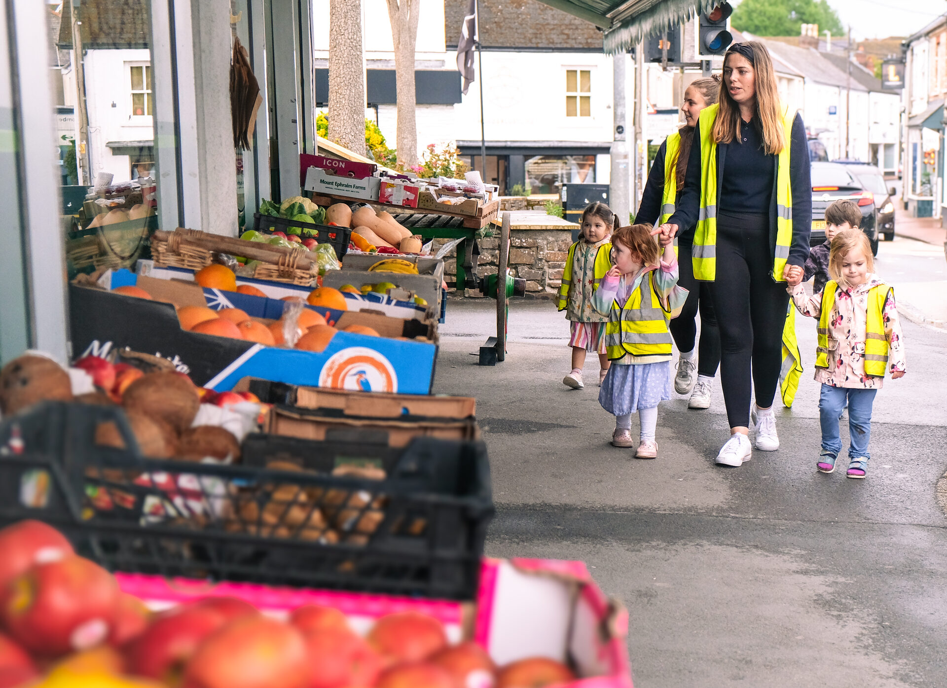 Children in high-visibility vests walking past a greengrocer in Exmouth town centre